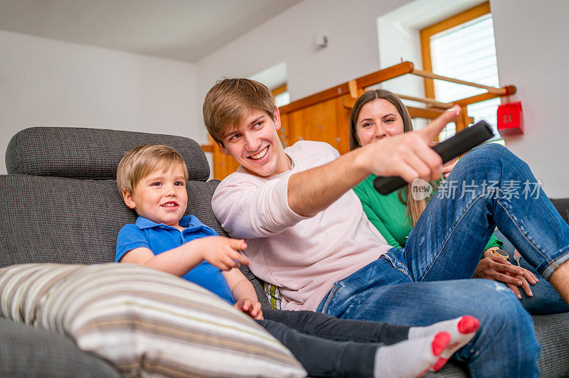 Young family sitting on a sofa and watching tv